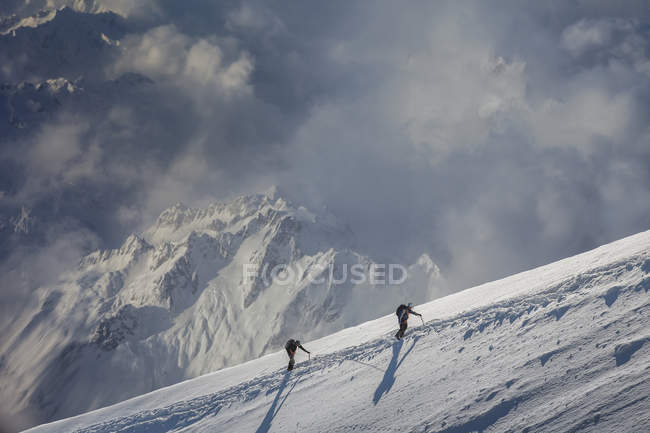 Dos escaladores que ascienden por una ladera nevada, Alpes, Cantón Wallis, Suiza - foto de stock