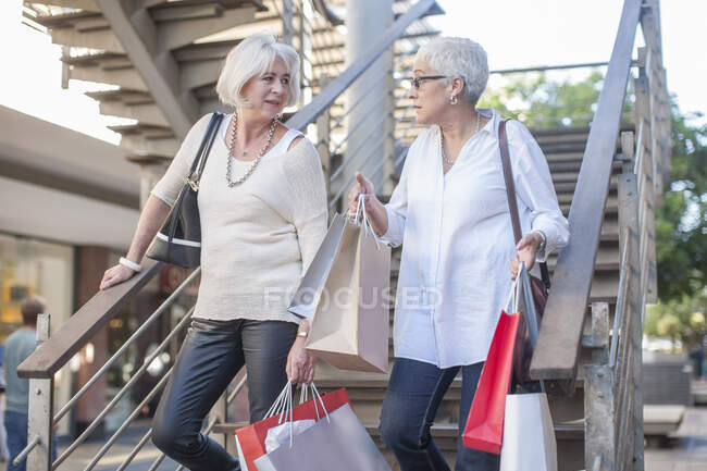 Кейптаун, Південна Африка, дві літні жінки, які йдуть по сходах з сумками для покупок. — стокове фото