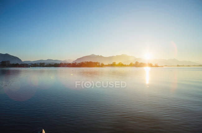 Mountains and sun over still lake — Stock Photo