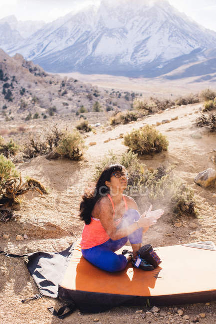 Женщина сидит на коврике для скалолазания, Баттермолочные валуны, Бишоп, Калифорния, США — стоковое фото
