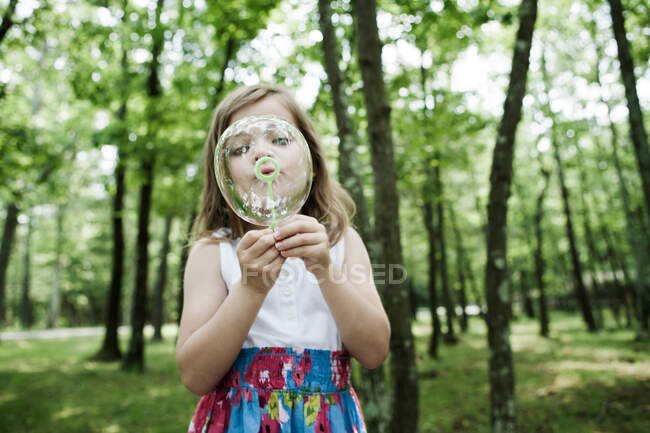 Chica soplando burbujas en el bosque - foto de stock