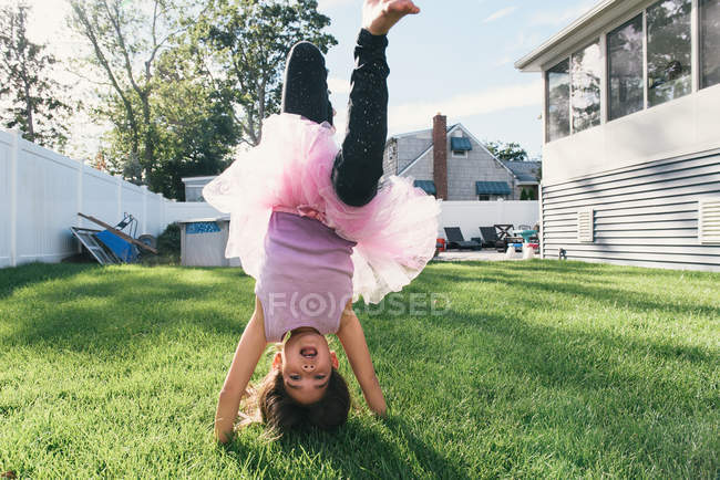 Girl in garden doing upside down handstand — Stock Photo