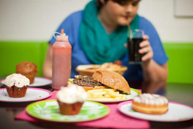 Jeune femme dans un café avec table de nourriture — Photo de stock