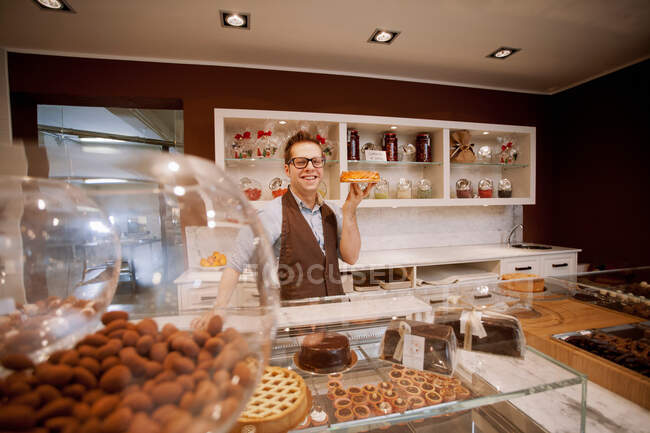 Cashier holding fruit cake in bakery — Stock Photo