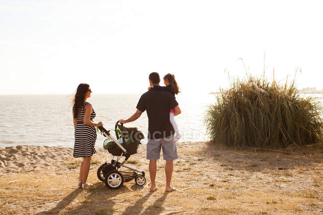 Familie steht am Strand und blickt aufs Meer — Stockfoto