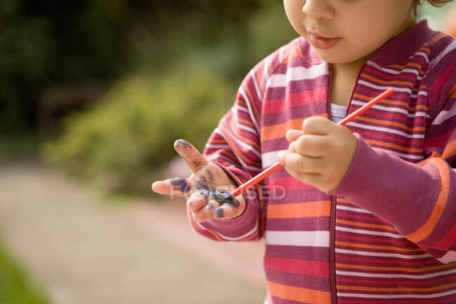 Маленькая девочка рисует руками — стоковое фото