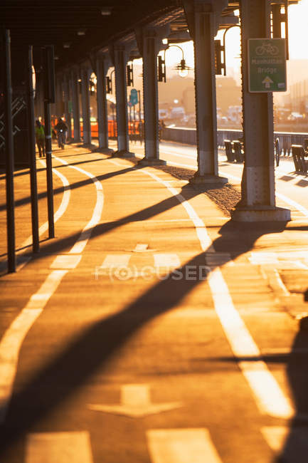 Piste cyclable sous le pont au coucher du soleil — Photo de stock