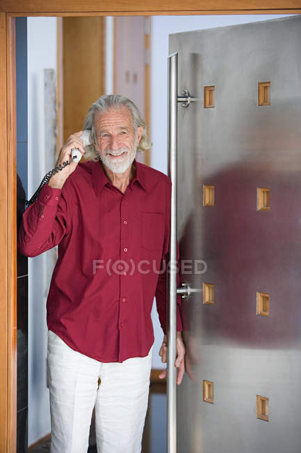 Homem com telefone em pé à porta — Fotografia de Stock