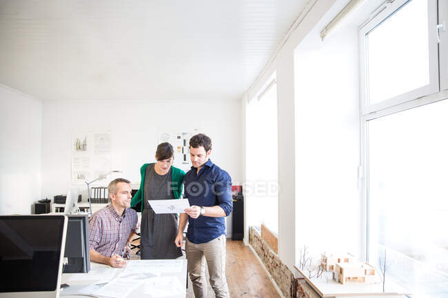 Colleagues at desk in office discussing paperwork — Stock Photo