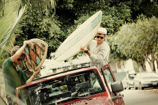 Hombres atando tablas de surf al techo del coche - foto de stock