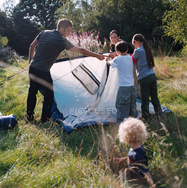 Семья, устанавливающая палатку — стоковое фото