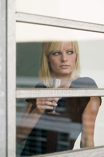 Femme par fenêtre avec verre à vin — Photo de stock