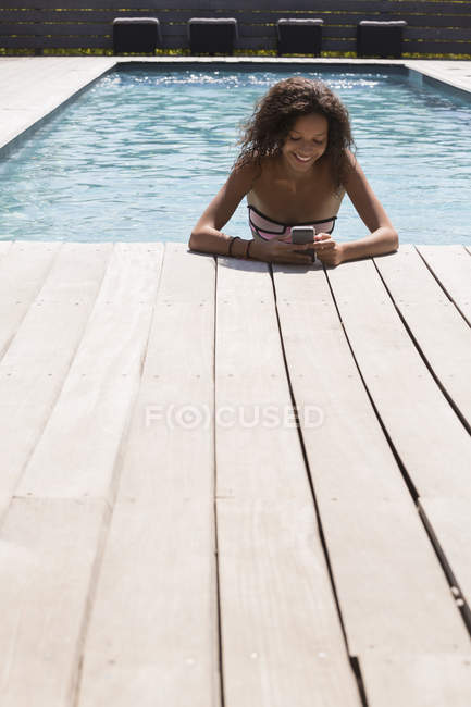 Chica en la piscina leyendo textos de teléfonos inteligentes, Cassis, Provenza, Francia - foto de stock