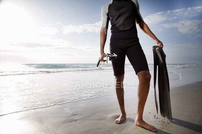 Ein Mädchen mit Rucksack im Badeanzug und schwarzer Jacke am Strand — Stockfoto