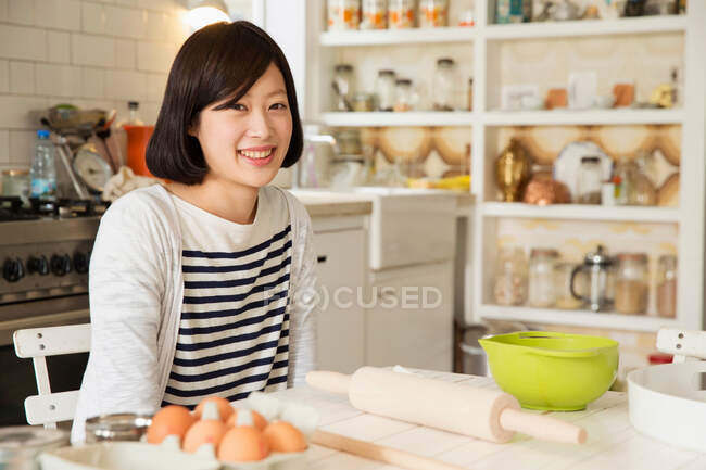 Портрет молодої жінки за кухонним столом з інгредієнтами для випічки — стокове фото