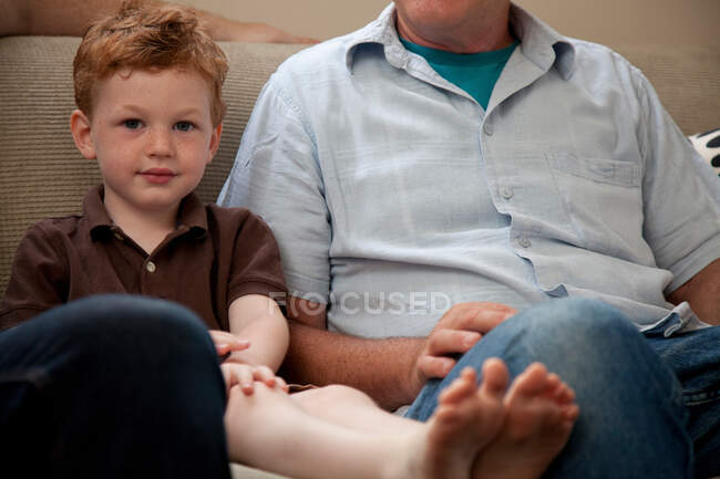 Niño en el sofá con el abuelo - foto de stock
