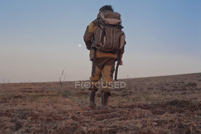 Людина, проходячи через поле, заднього виду, низький кут зору — Stock Photo