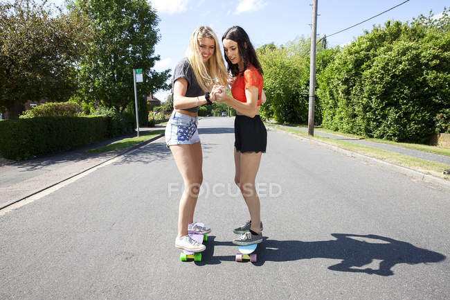 Две молодые женщины катаются на скейтборде по дороге — стоковое фото
