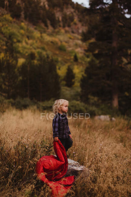 Junge steht auf dem Feld und hält Schlafsack in der Hand, Mineral King, Sequoia National Park, Kalifornien, USA — Stockfoto