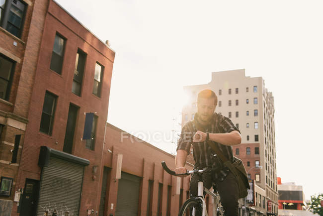 Male cycle messenger checking time on wristwatch — Stock Photo