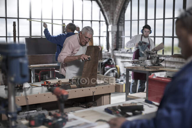 Cape Town, South Africa, elderly woodworker sanding down wood in workshop — Stock Photo