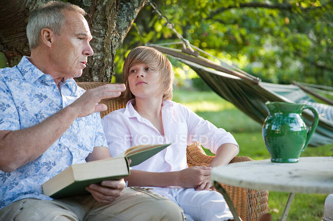 Padre e figlio con libro, in conversazione — Foto stock