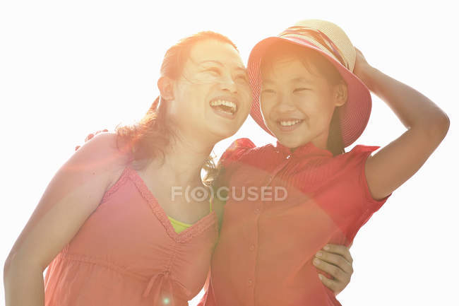 Retrato de mujer abrazando a su hija a la luz del sol - foto de stock