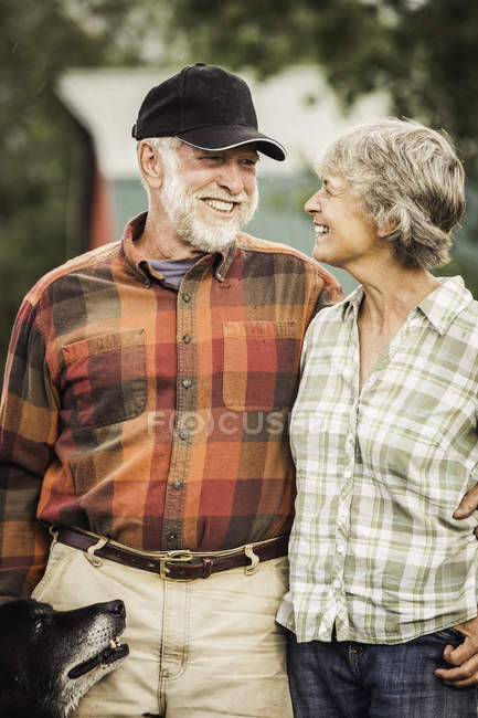 Couple with dog face to face smiling — Stock Photo