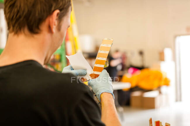Arbeiter schaut sich Uhr in Siebdruckwerkstatt an — Stockfoto