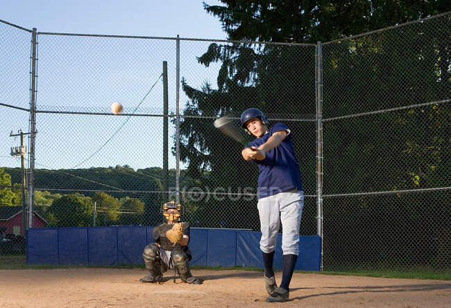 Adolescente columpiándose para golpear el béisbol - foto de stock