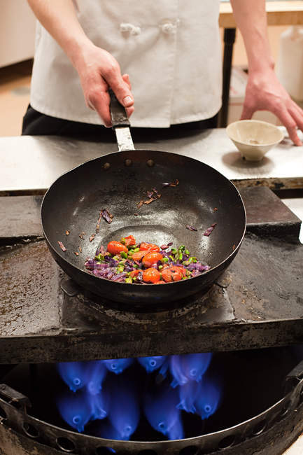 Homme chef friture avec wok dans la cuisine commerciale — Photo de stock