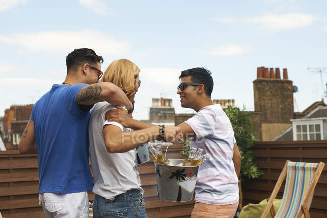 Drei männliche Freunde tragen Eimer mit Flaschenbier bei Dachparty — Stockfoto