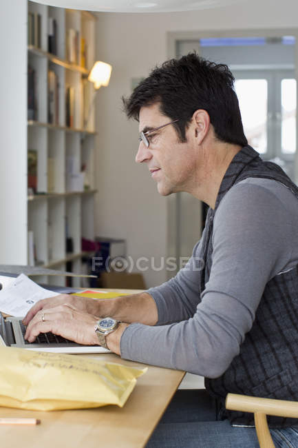 Зрелый бизнесмен использует ноутбук дома — стоковое фото