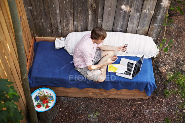 Людина використовує ноутбук на дивані на відкритому повітрі — стокове фото