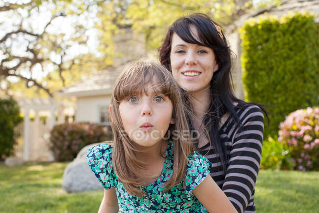 Retrato de mãe e filha puxando o rosto no jardim — Fotografia de Stock