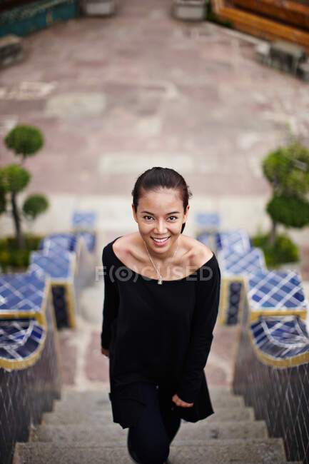 Mulher sorrindo em degraus ornamentados — Fotografia de Stock