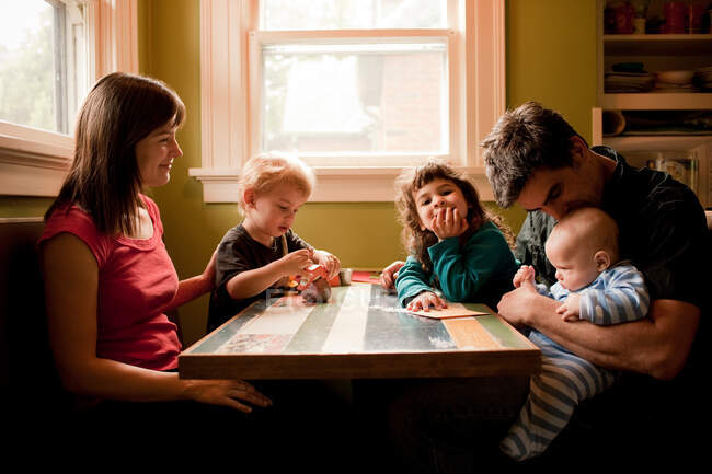 Семья сидит за кухонным столом — стоковое фото