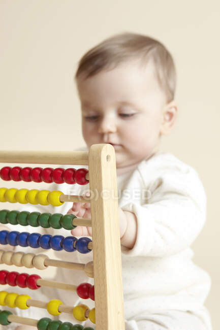 Close up studio portrait of baby girl playing with abacus — Stock Photo