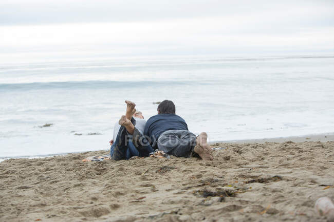 Зрелая пара лежит на пляже и смотрит на море — стоковое фото