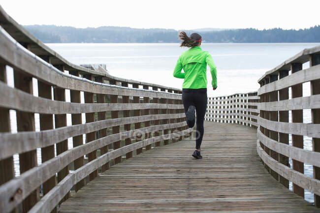 Donna che corre su una banchina di legno — Foto stock