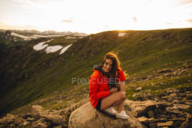 Femme assise sur un rocher et regardant une caméra, Rocky Mountain National Park, Colorado, USA — Photo de stock