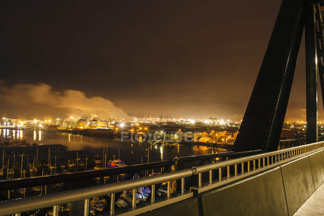 Vista lejana de los tanques de almacenamiento de petróleo en el muelle de Puget Sound por la noche, Tacoma, estado de Washington, EE.UU. - foto de stock