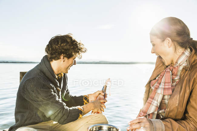 Couple by lake opening champagne — Stock Photo