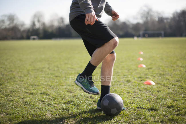Cintura para baixo do jovem praticando futebol no campo de jogo — Fotografia de Stock