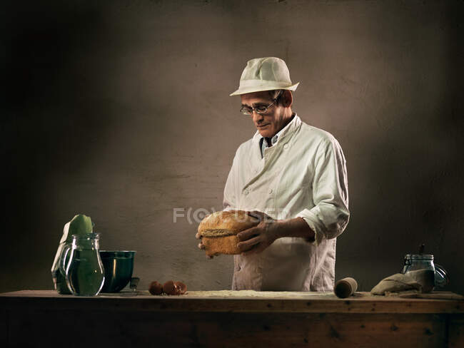 Пекарь держит буханку хлеба — стоковое фото