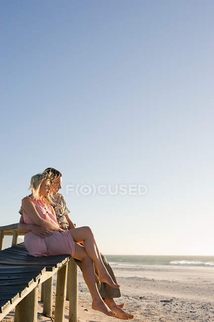 Un couple assis sur une jetée — Photo de stock