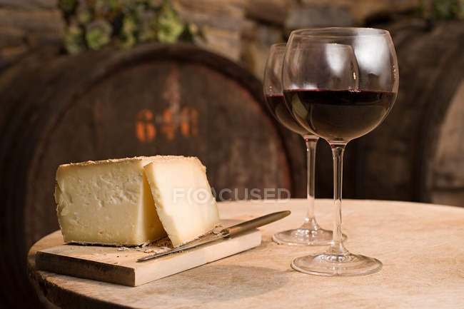 Cheese head and red wine glasses on table — Stock Photo