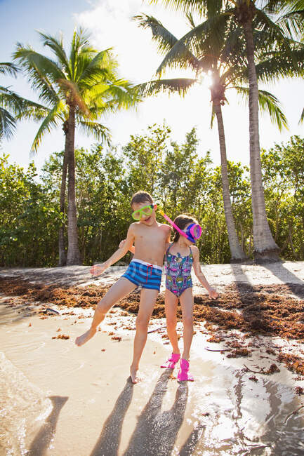 Dos niños jugando en la playa, usando trajes de baño y tubos - foto de stock