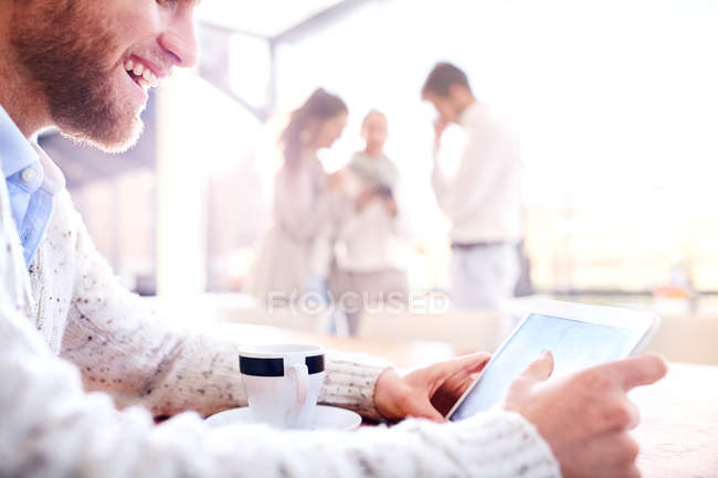 Jungunternehmer schaut im Büro auf digitales Tablet — Stockfoto