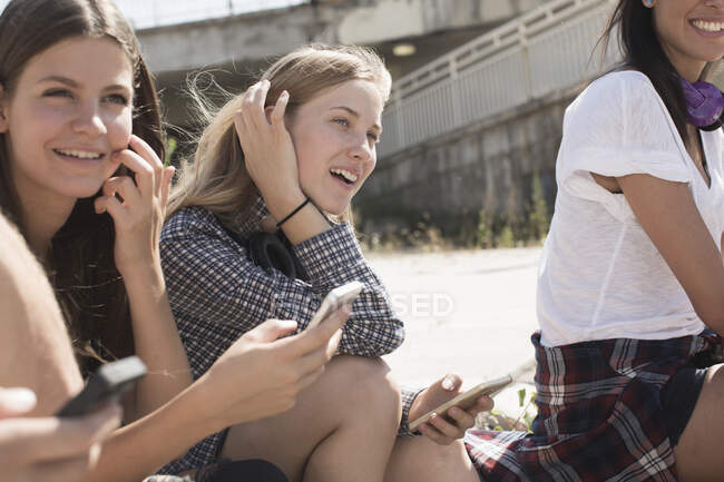 Друзья сидят вместе, используя смартфоны — стоковое фото
